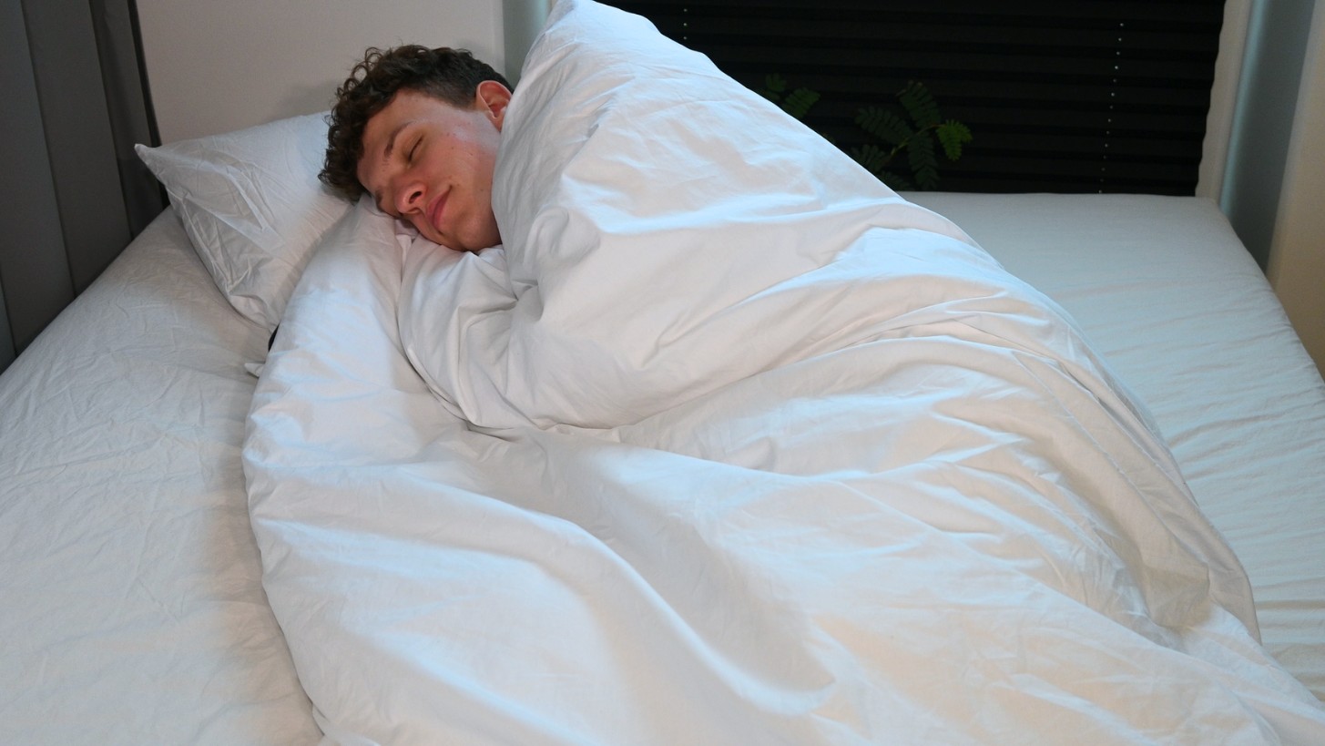 Mand sover med tyngdedyne i en seng