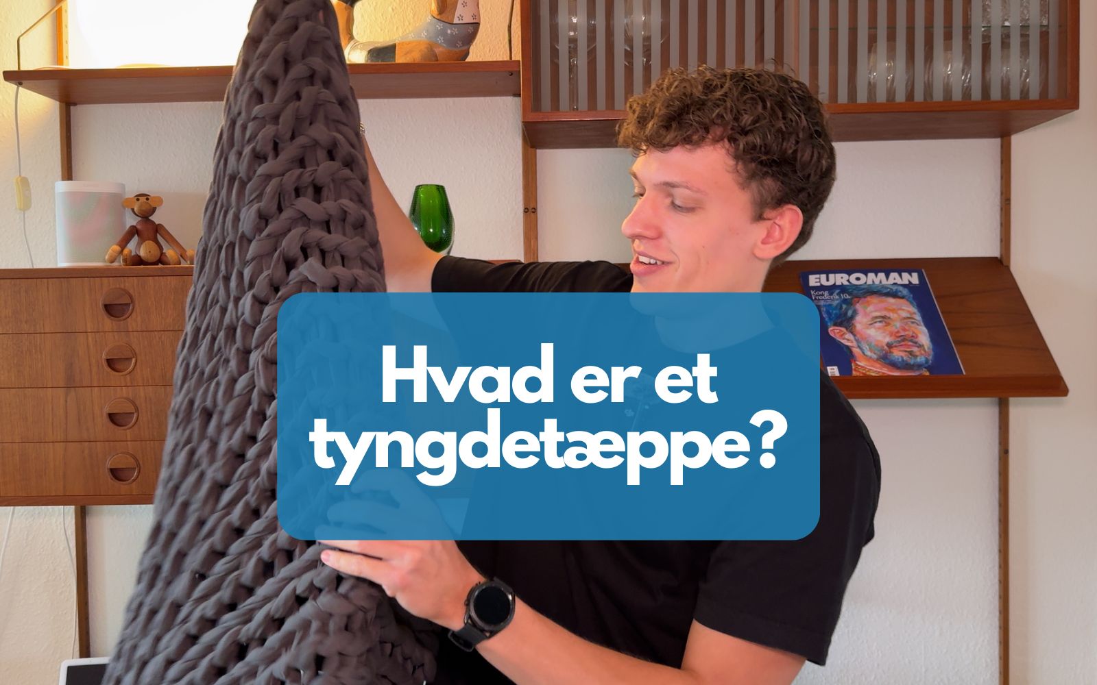 En person holder et tyngdetæppe op i luften hvor der står "Hvad er et tyngdetæppe?"