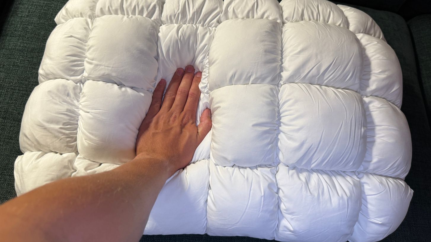 En hånd trykker ned på CloudOne hovedpuden