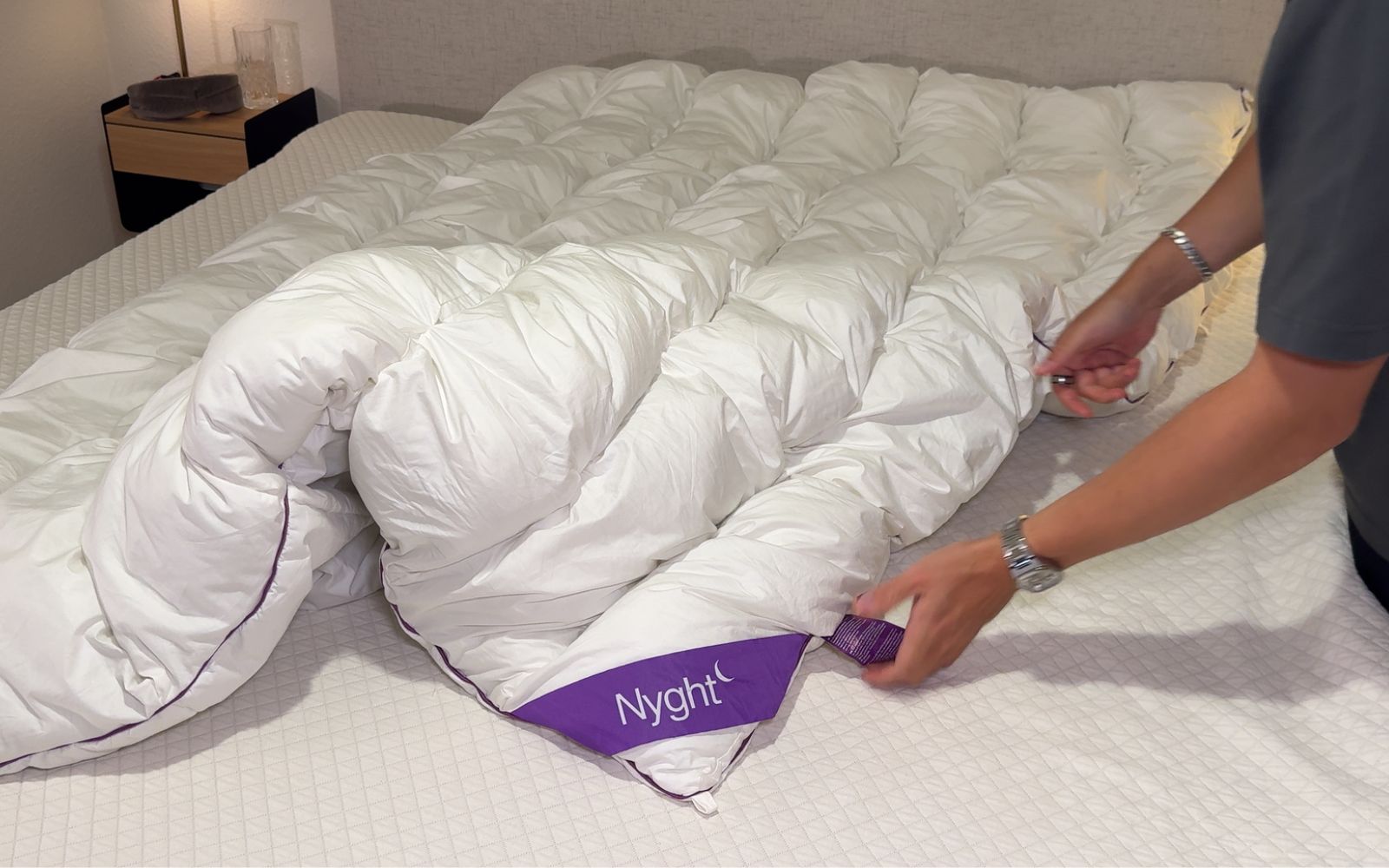 Nyght HybridDuvet ligger på en seng med en som tester den